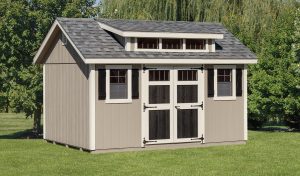 Transom dormer shed with tan siding, white trim, black double doors, 2 windows with black shutters, gray roofing, and transom dormer windows.