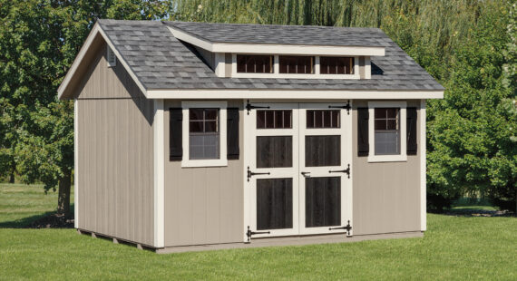 Transom dormer shed with tan siding, white trim, black double doors, 2 windows with black shutters, gray roofing, and transom dormer windows.