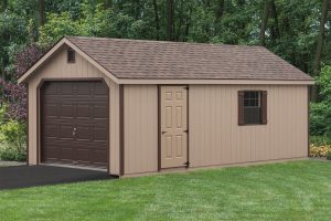 A-Frame & cape style garage with light brown wood siding, dark brown trim, dark brown rolling garage door, brown roofing, a window with dark brown shutters, and a single entry light brown side door.