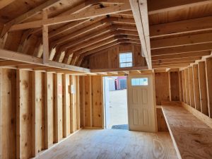 Interior of a shed with multiple lofts, a workbench, and a white panel door with windows.